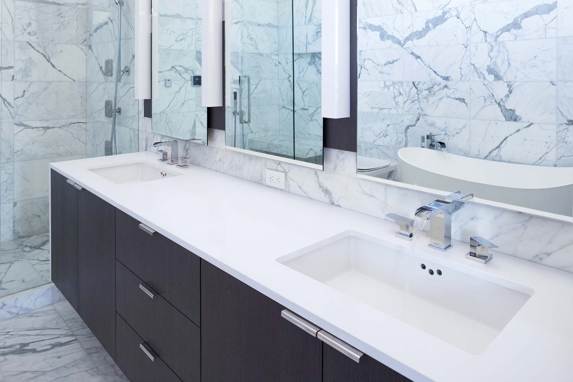 Spacious bathroom with two bathrooms and white tiles at a custom home in South Vancouver.