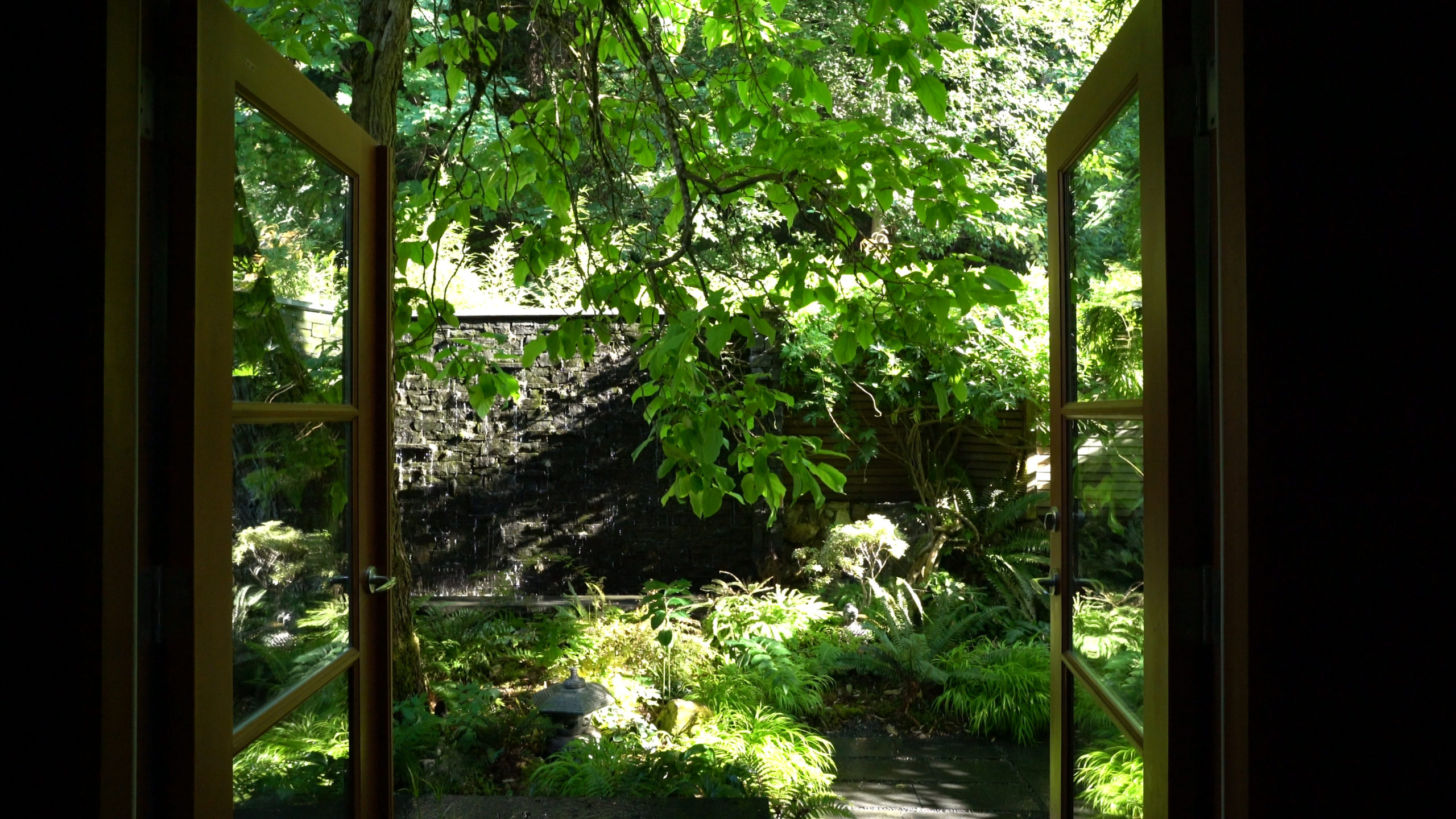 Yard design with cascading waterfall and green plants at a custom home on Bowen Island.