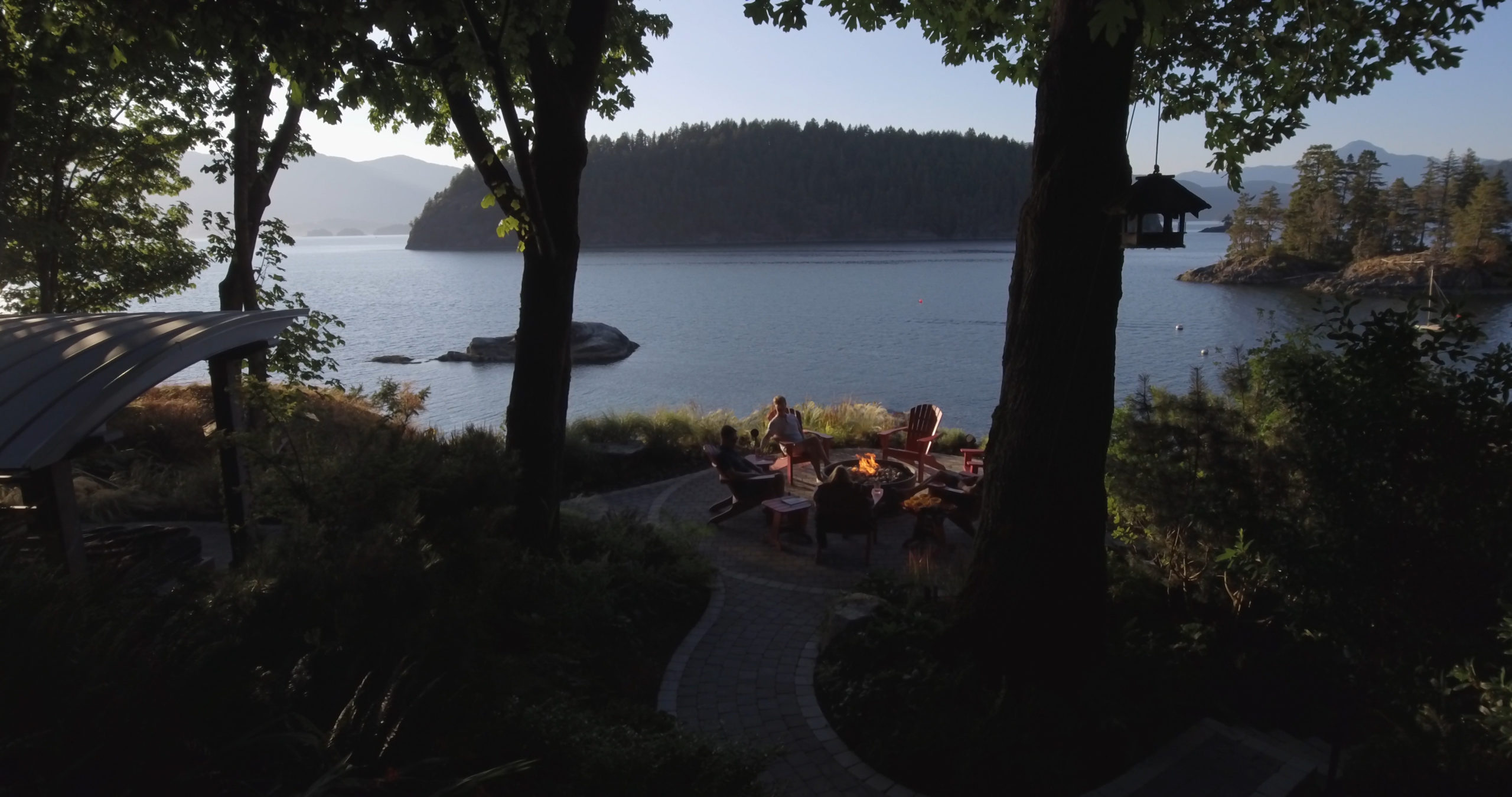 Family gathers together in front of a firebowl with a view of the ocean at a custom home on Bowen Island.