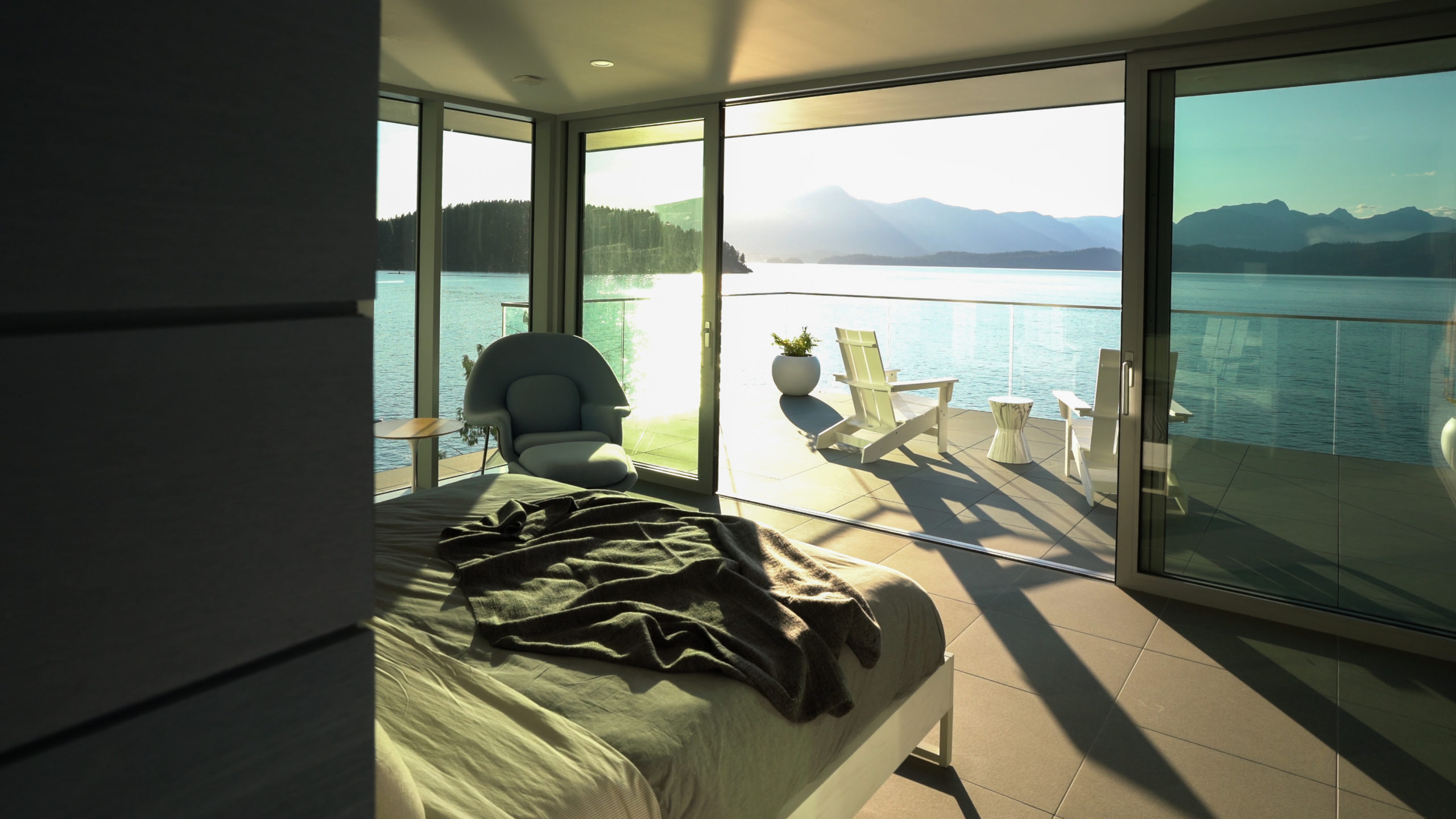 Master bedroom with a modern design, big windows, balcony, and ocean view on Bowen Island.